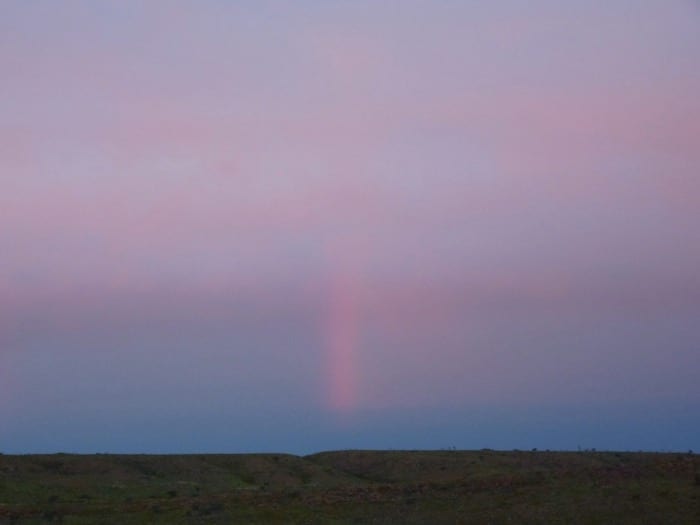 The pink vertical streak is actually a small rain shower. Devils Marbles.