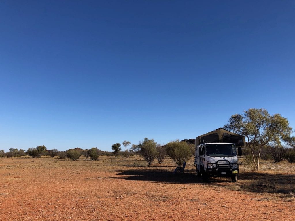 Camper under an ancient volcanic range, Plenty Highway.