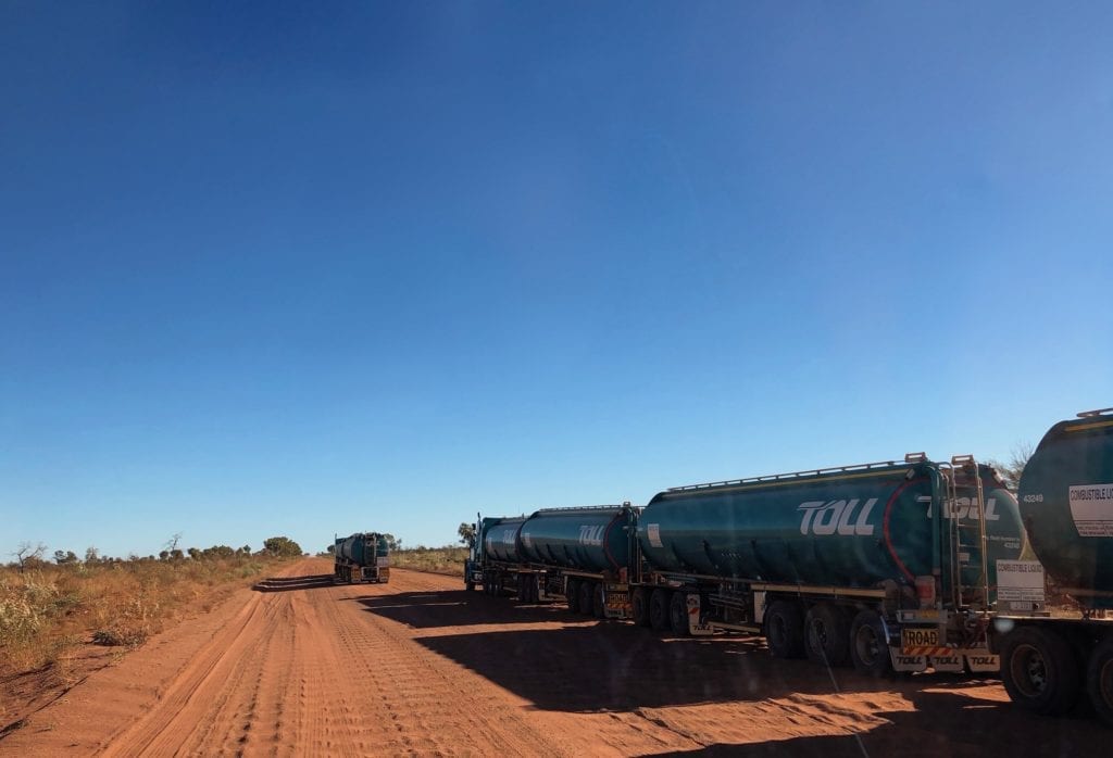 Two roadtrains stopped on the road to change a tyre. Tanami Road.