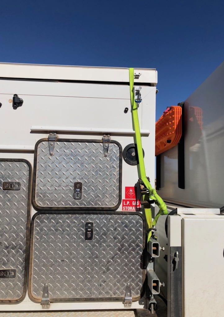 A ratchet strap temporarily holding our camper closed after a latch broke on the Finke track.