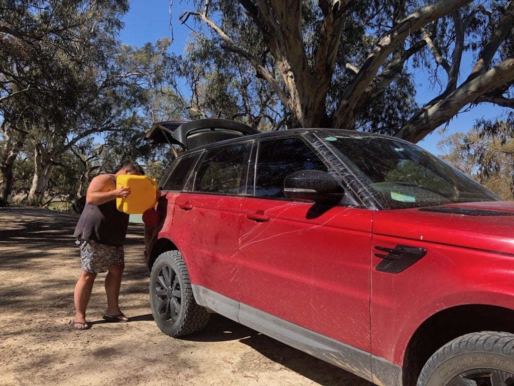 Emptying a jerry can into the Range Rover Sport.