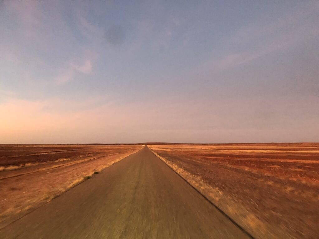 Early morning light on a long straight road. Long-term travel.