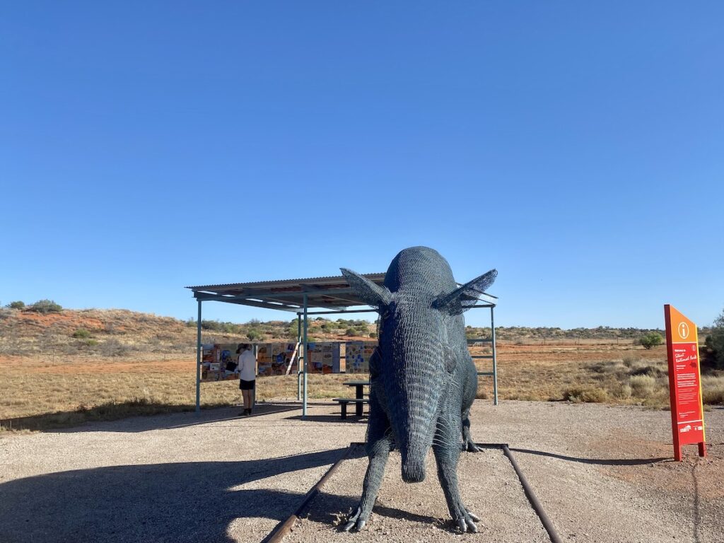 Talpero wire sculpture with covered picnic and interpretive sign boards in the background.