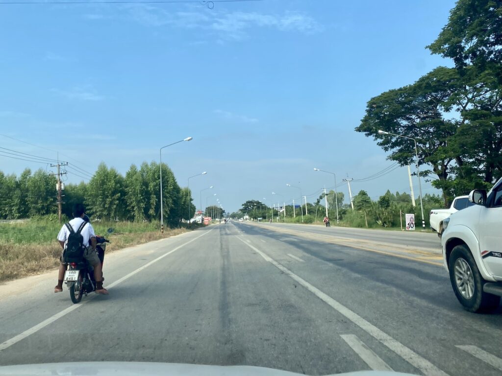 Two young teenagers on a motorbike on a two lane freeway. Driving in Thailand.