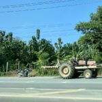 Driving in Thailand. Tractor driving along the side of a dual lane freeway.